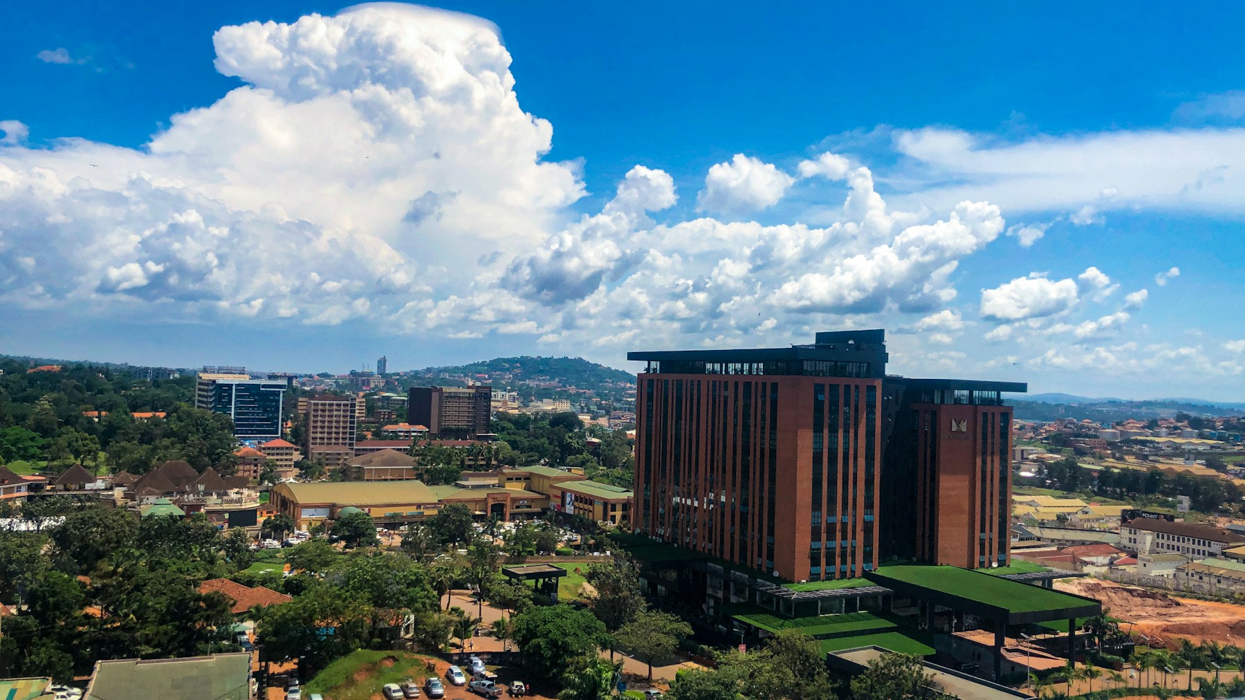Kampala skyline and green hills beneath a cloud-filled sky